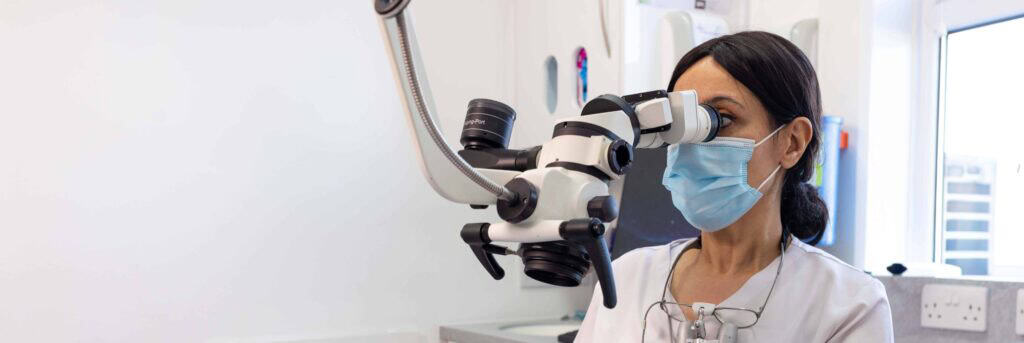 Dentist using microscope for detailed dental examination in clinic.